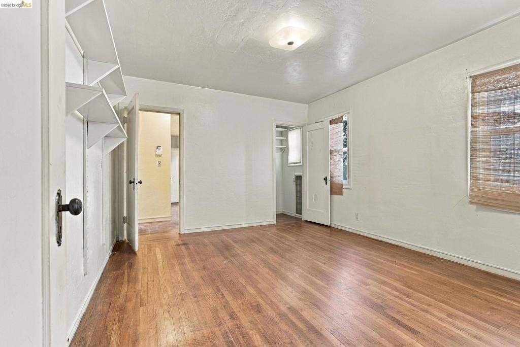 2901 Sheffield Ave, Oakland, CA 94602 Interior space featuring wood-finish flooring, built-in shelving, white textured walls, and a recessed closet