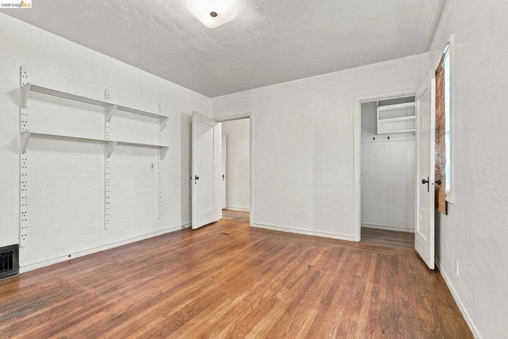 2901 Sheffield Ave, Oakland, CA 94602 Interior room featuring wood-finish flooring, adjustable wall-mounted shelving, overhead dome lighting, and a closet with built-in storage