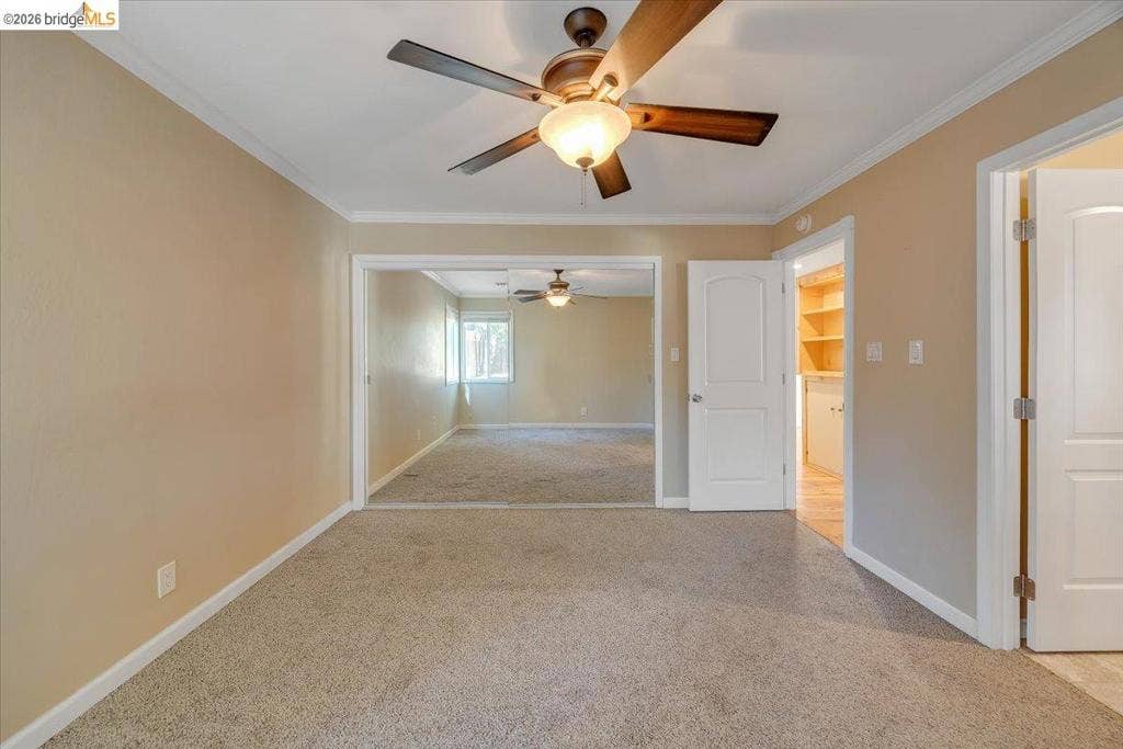 5827 Lookout Ct, CA 95233 Interior space featuring neutral wall paint, carpeting, a ceiling fan with integrated lighting, a solid-core interior door, and built-in shelving