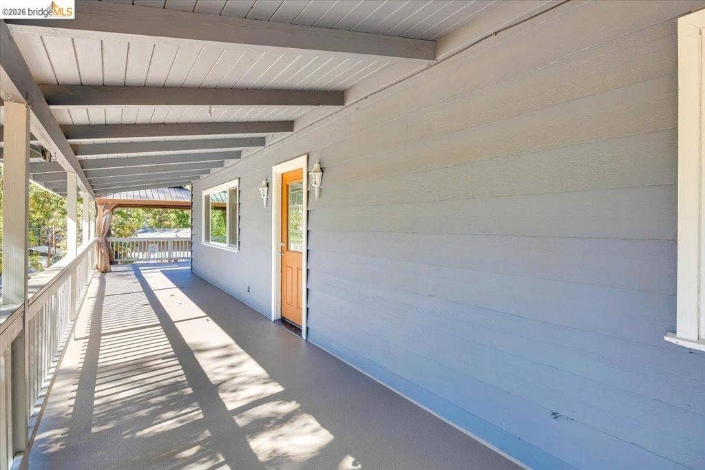 5827 Lookout Ct, CA 95233 Covered wraparound porch featuring horizontal lap siding, a tongue-and-groove ceiling, protective railing, and wall-mounted exterior sconces