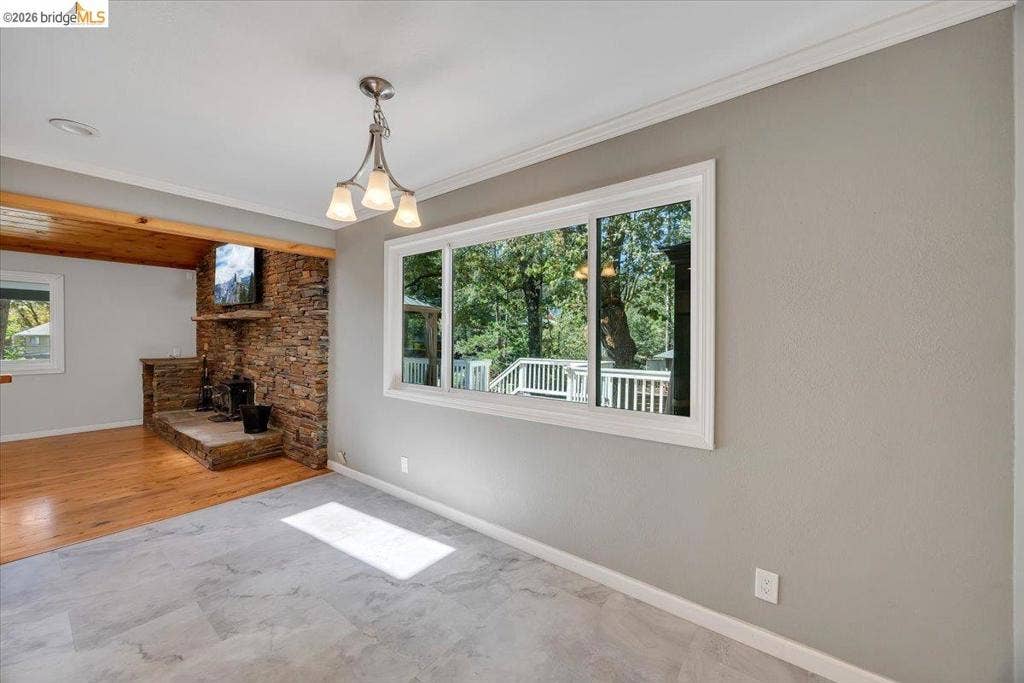 5827 Lookout Ct, CA 95233 Stone-faced fireplace with hearth, wood-finish flooring, large sliding window, and three-bulb pendant lighting fixture