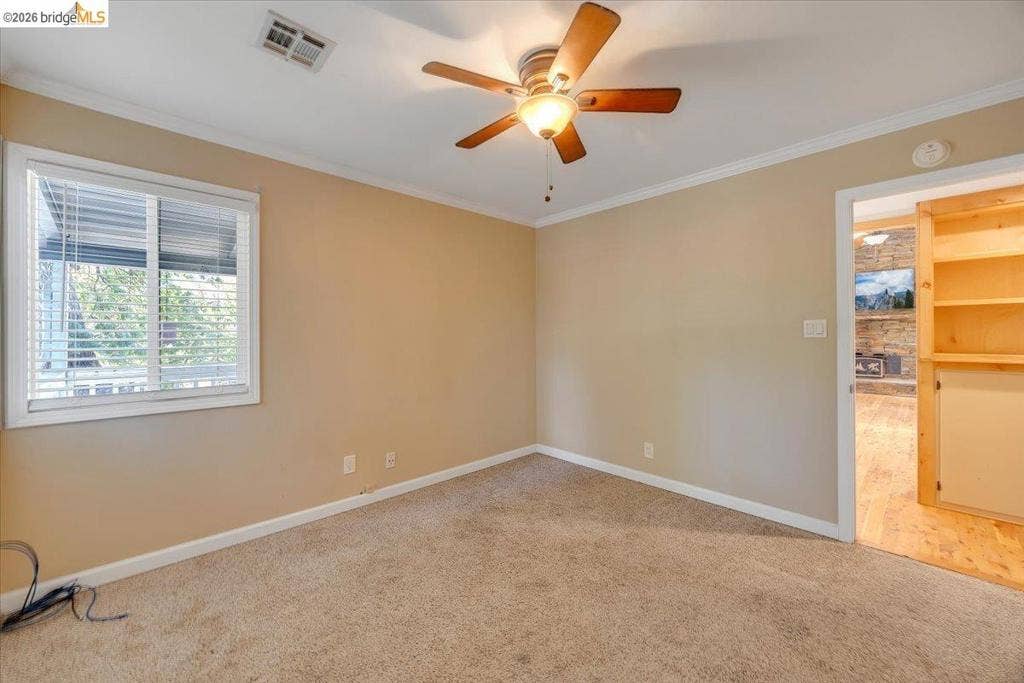 5827 Lookout Ct, CA 95233 Neutral-toned room featuring a central ceiling fan with integrated lighting, wall-to-wall carpeting, and a double-hung window