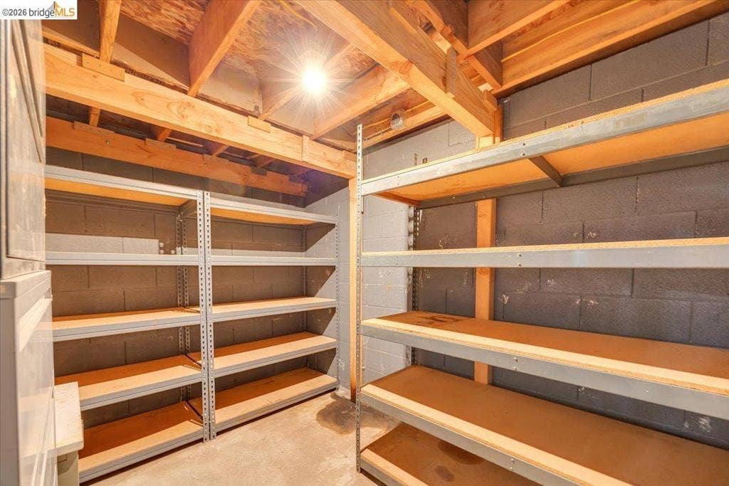 5827 Lookout Ct, CA 95233 Storage area featuring exposed timber ceiling joists and painted concrete masonry block walls