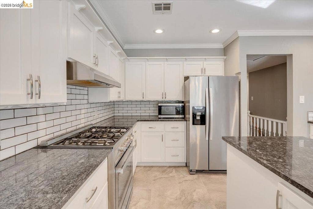 5827 Lookout Ct, CA 95233 Kitchen featuring white shaker-style cabinetry, stone-finish countertops, stainless steel appliances, a white subway tile backsplash, and neutral tile flooring