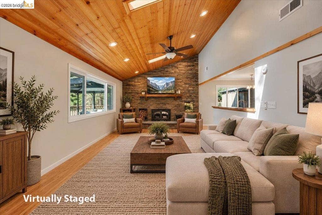 5827 Lookout Ct, CA 95233 Vaulted ceiling with exposed wood paneling, stone masonry fireplace featuring a wood mantel, recessed lighting, and wood-finish flooring