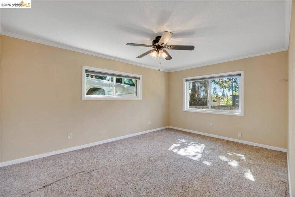 5827 Lookout Ct, CA 95233 Room featuring neutral-toned walls, carpeting, crown molding, and a central ceiling fan with integrated lighting