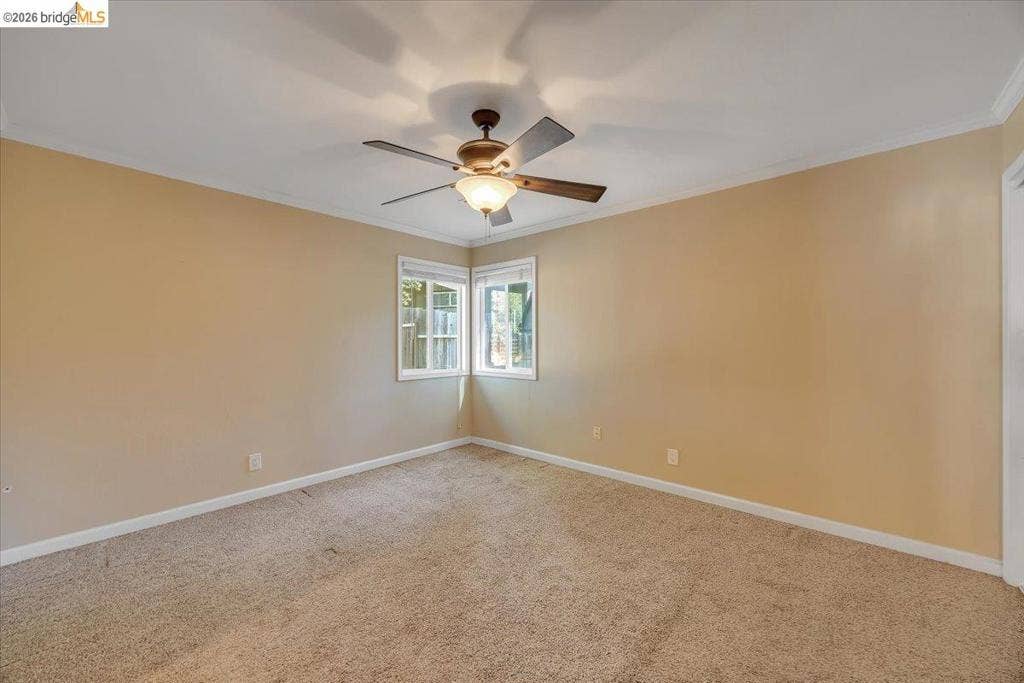 5827 Lookout Ct, CA 95233 Neutral-toned interior featuring wall-to-wall carpeting, crown molding, and a central ceiling fan with integrated lighting