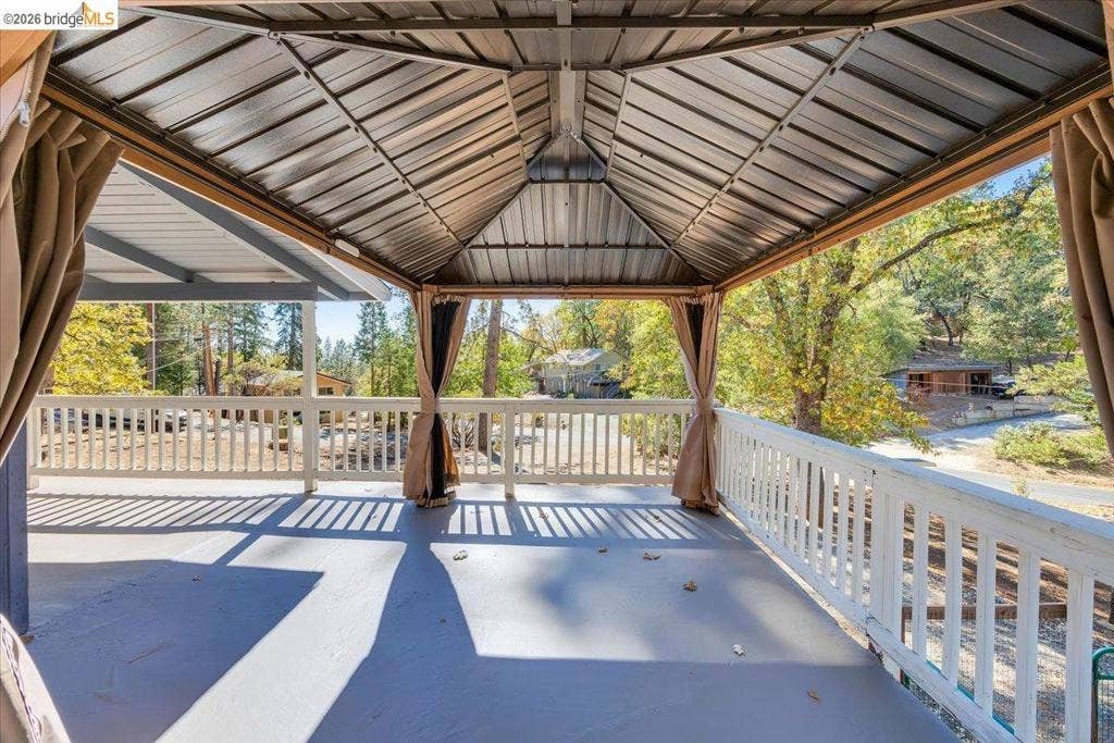 5827 Lookout Ct, CA 95233 Covered deck featuring a metal-roof gazebo, white wood-slat railing, and solid flooring