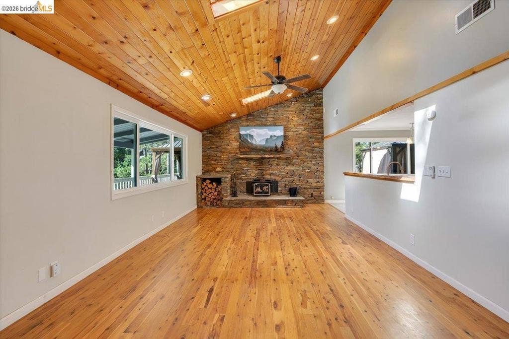 5827 Lookout Ct, CA 95233 Vaulted wood-paneled ceiling, stone accent wall with built-in wood storage, wood-finish flooring, recessed lighting, and ceiling fan