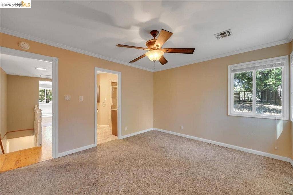 5827 Lookout Ct, CA 95233 Neutral-toned interior featuring wall-to-wall carpeting, crown molding, and a central ceiling fan with integrated lighting