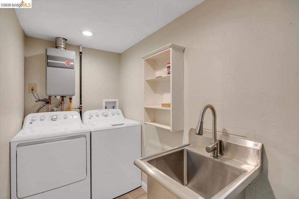 5827 Lookout Ct, CA 95233 Utility area featuring a wall-mounted tankless water heater, stainless steel utility sink with a high-arc pull-down faucet, and built-in wall shelving
