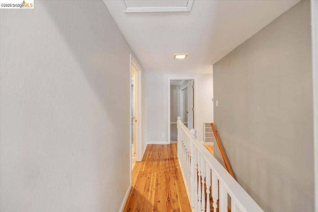 5827 Lookout Ct, CA 95233 Hallway featuring wood-finish flooring, white spindle railing, and a wood handrail