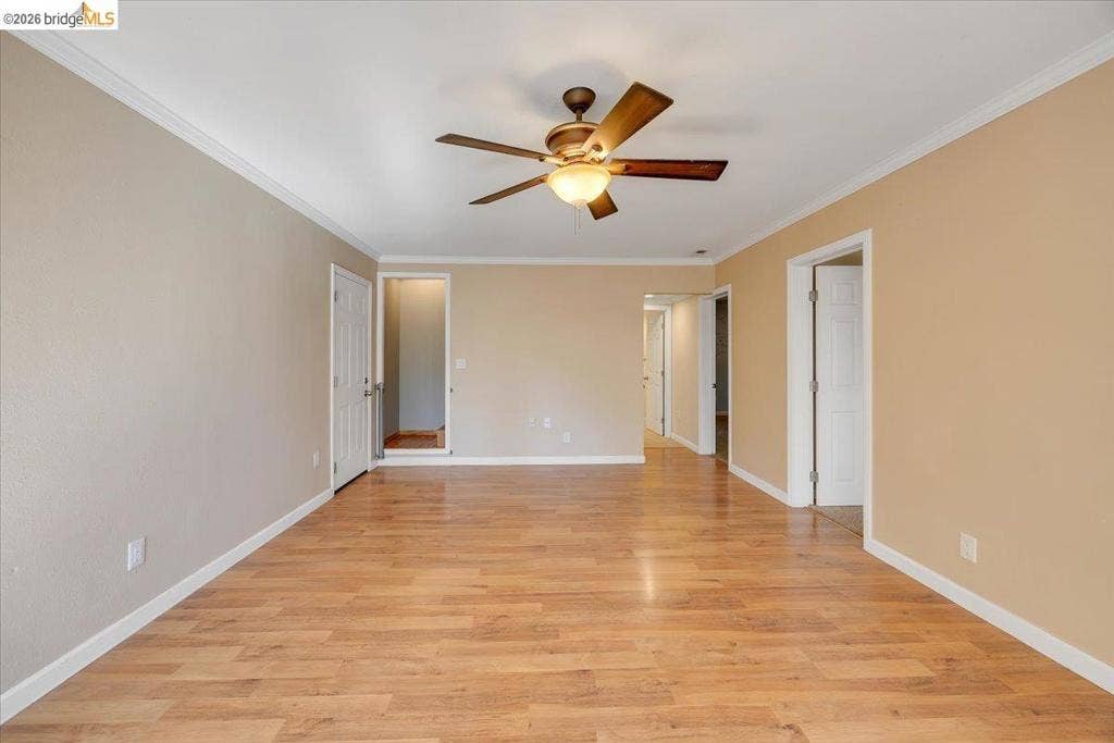 5827 Lookout Ct, CA 95233 Room featuring wood-finish flooring, neutral wall paint, crown molding, and a central ceiling fan with an integrated light fixture