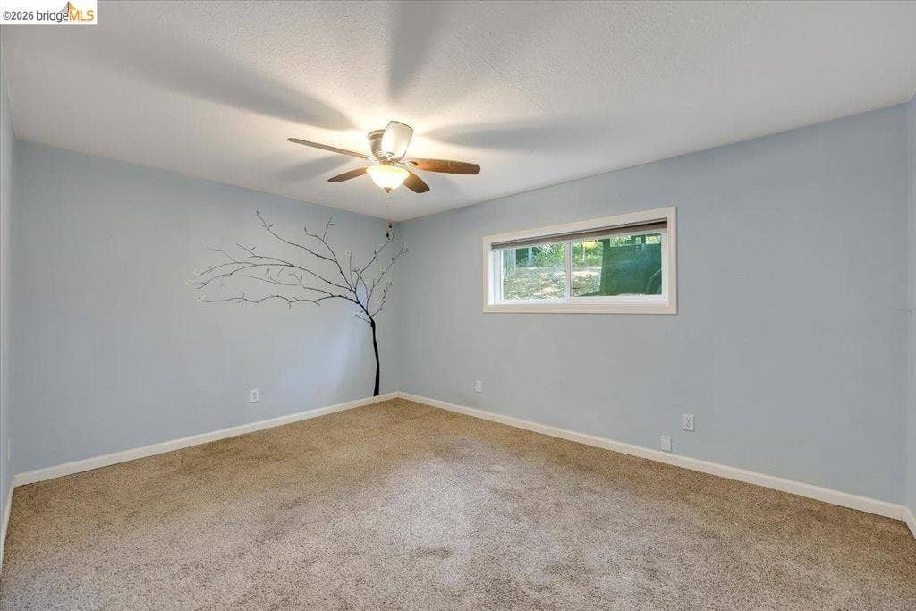 5827 Lookout Ct, CA 95233 Room featuring wall-to-wall carpeting, a ceiling fan with integrated light fixture, and a horizontal sliding window