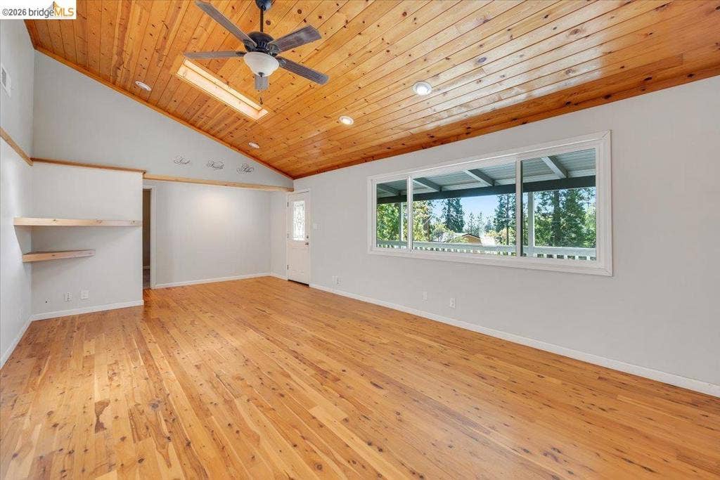 5827 Lookout Ct, CA 95233 Vaulted ceiling with tongue-and-groove wood paneling, wood-finish flooring, recessed lighting, built-in wall shelving, and a large picture window