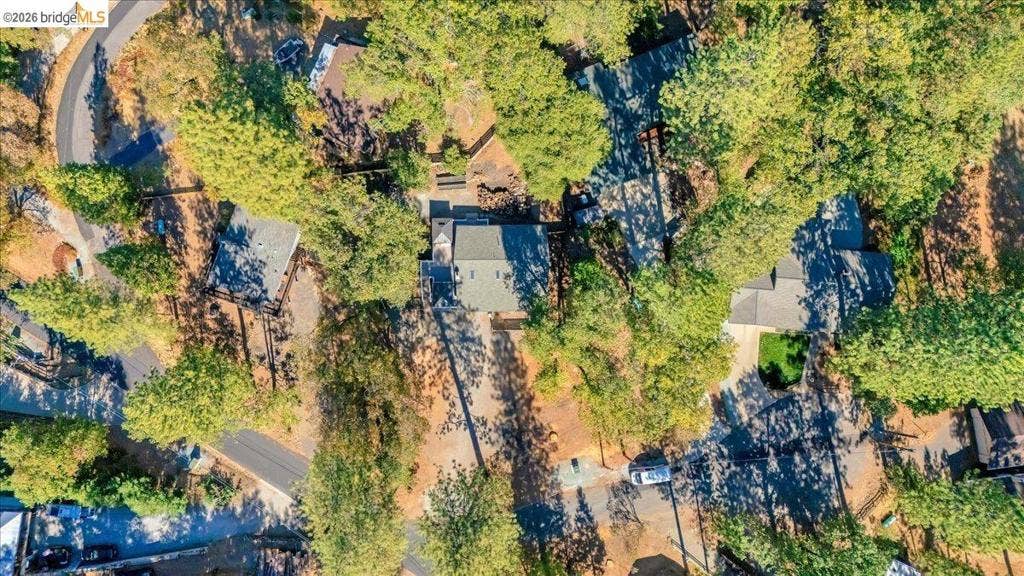 5827 Lookout Ct, CA 95233 Aerial perspective of a multi-structure property featuring dense woodland, asphalt driveways, and composition shingle roofing