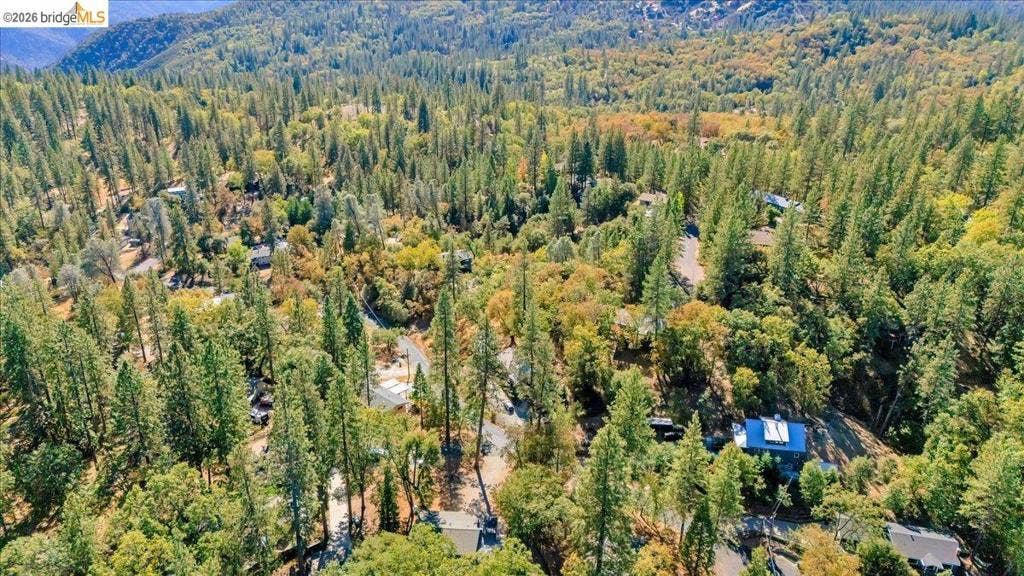 5827 Lookout Ct, CA 95233 Aerial perspective of a heavily wooded landscape featuring mature evergreen and deciduous trees, winding paved roads, and rolling mountain terrain