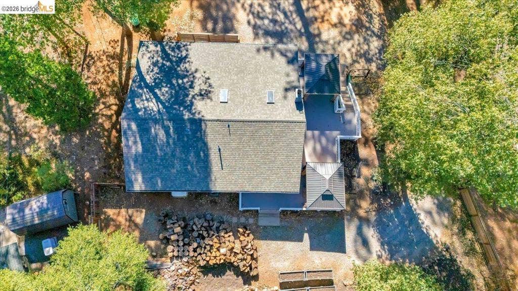 5827 Lookout Ct, CA 95233 Aerial perspective of a detached residence featuring a pitched shingle roof, two integrated skylights, elevated wood-finish decking, and an attached gazebo structure