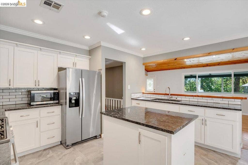 5827 Lookout Ct, CA 95233 Kitchen featuring white shaker cabinetry, stone countertops, a central island, subway tile backsplash, and recessed lighting