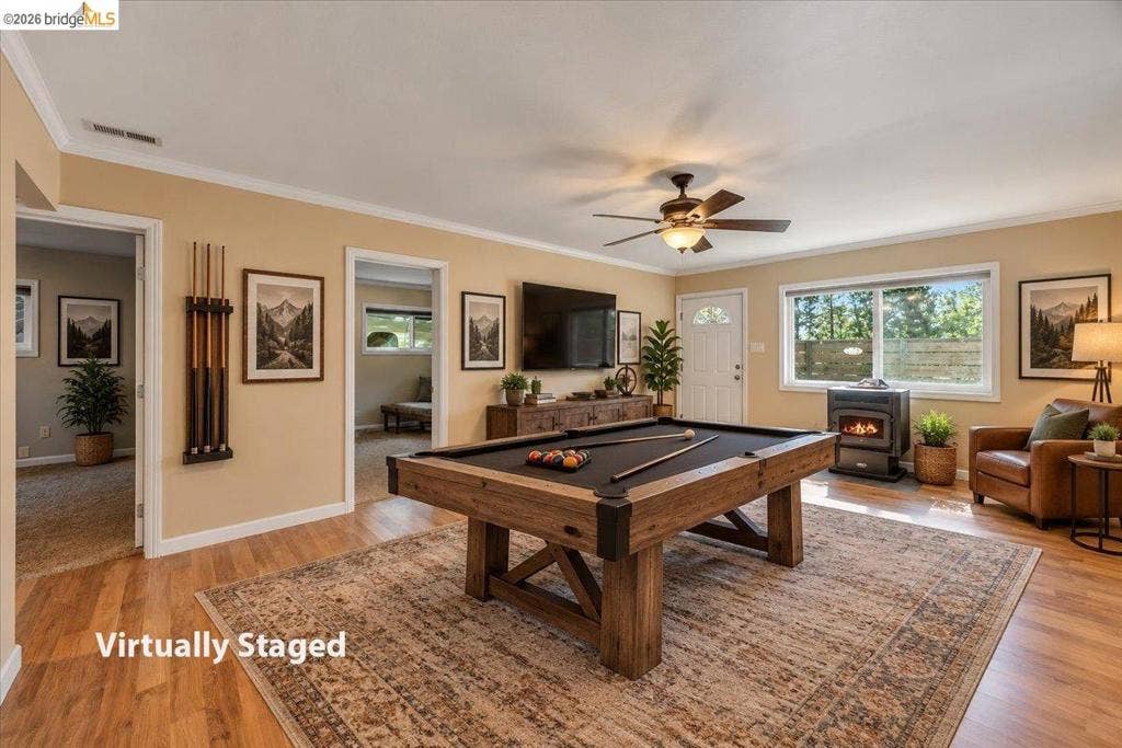 5827 Lookout Ct, CA 95233 Open-concept room featuring wood-finish flooring, a freestanding heating stove, a central ceiling fan, and large windows