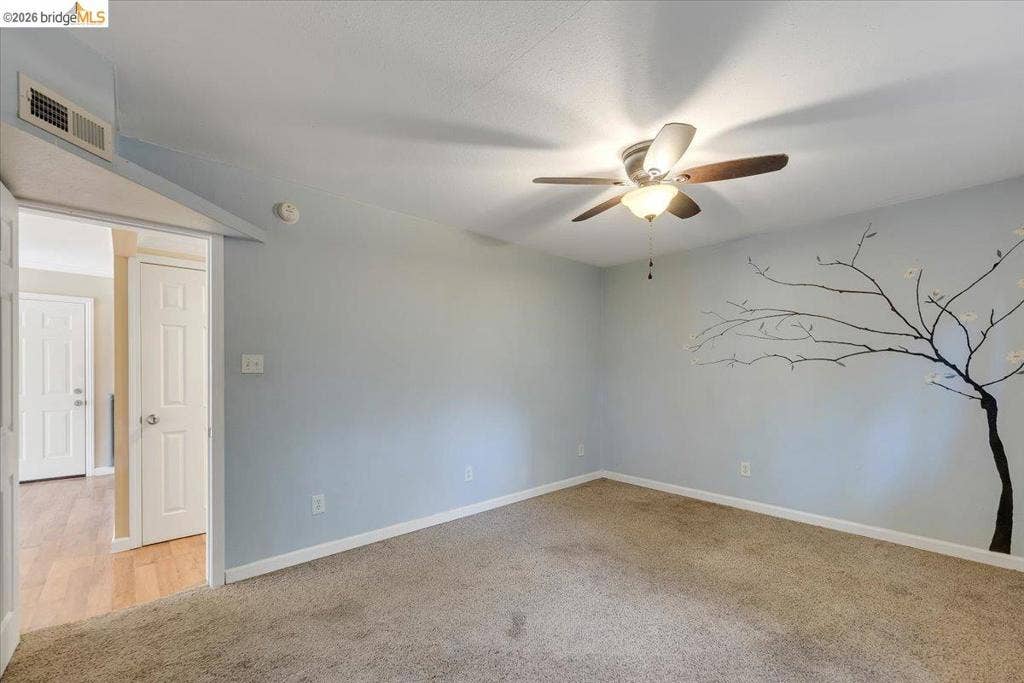 5827 Lookout Ct, CA 95233 Neutral-toned wall-to-wall carpeting and a central ceiling fan with integrated lighting