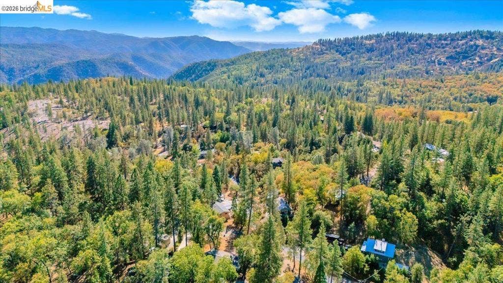 5827 Lookout Ct, CA 95233 Aerial perspective featuring an expanse of mature coniferous forest, rolling hills, and distant mountain topography