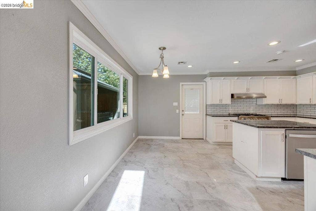 5827 Lookout Ct, CA 95233 Kitchen featuring white shaker-style cabinetry, stone-finish countertops, subway tile backsplash, stainless steel range hood, and tile flooring