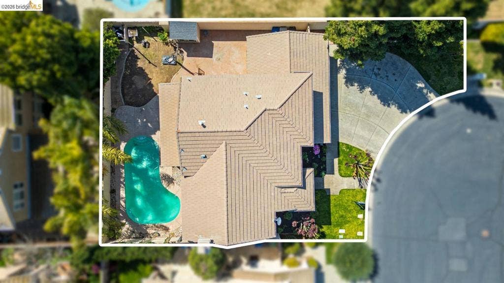 4600 Via Terreno, Modesto, CA 95357 Aerial perspective of the property featuring a concrete driveway, multi-gabled tile roof, swimming pool, and landscaped lawn areas