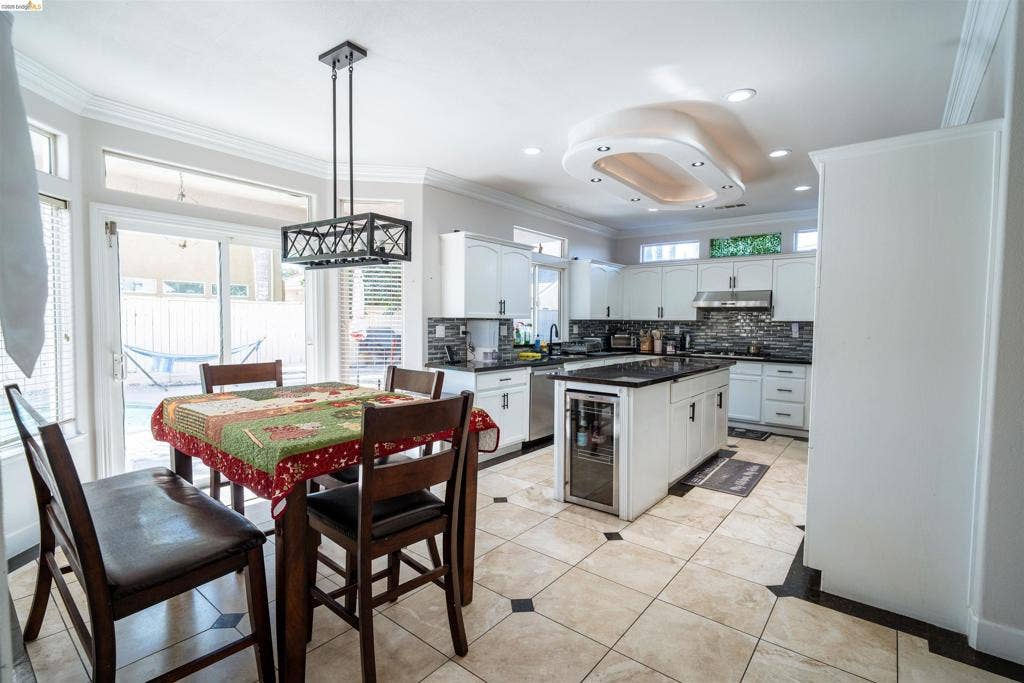 4600 Via Terreno, Modesto, CA 95357 Kitchen featuring white cabinetry, dark stone countertops, an integrated beverage cooler, tile flooring with decorative inserts, and custom recessed ceiling lighting