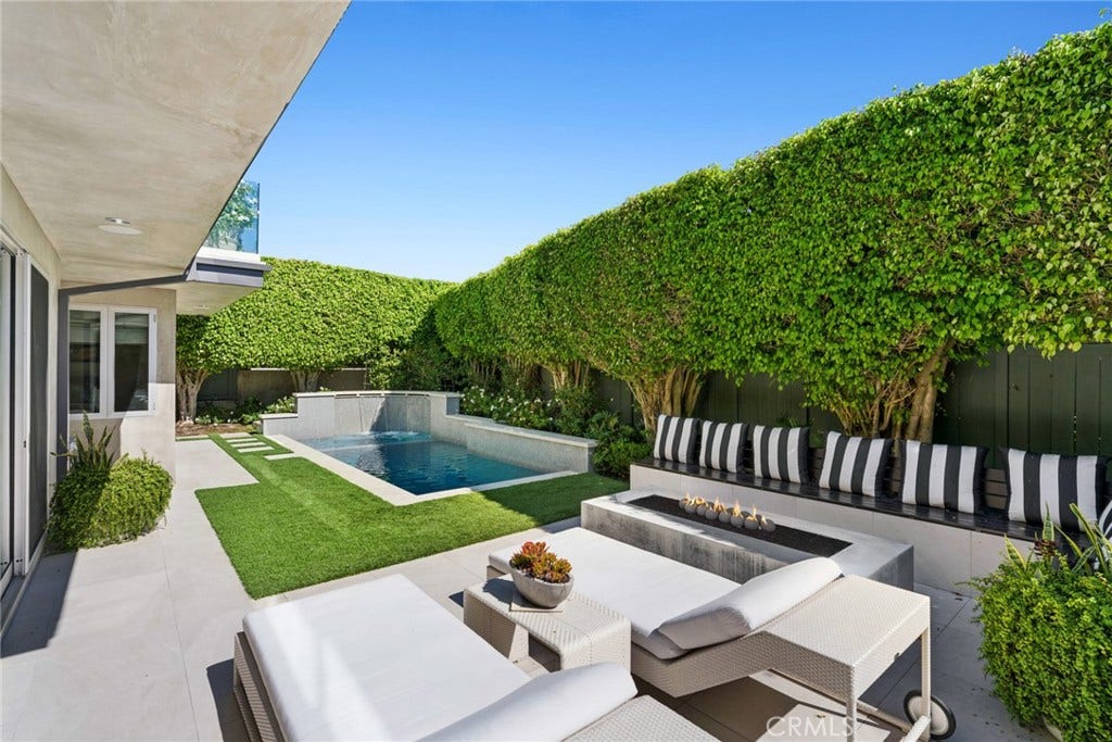 The lower level opens directly to a completely private outdoor setting featuring a generous yard, resort-inspired pool and spa, and an inviting seating area centered around an outdoor fireplace creating an exceptional environment for year-round relaxation and entertaining.
