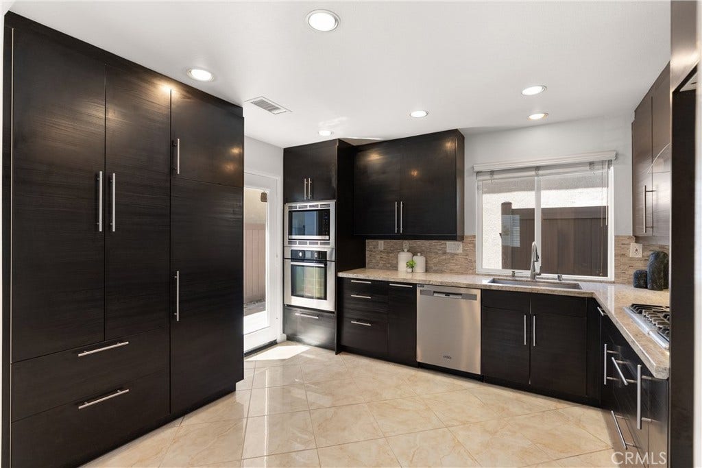 15 Poppyfield, Rancho Santa Margarita, CA 92688 Beautifully remodeled kitchen featuring rich espresso cabinetry, granite countertops, stainless steel appliances, a gas cooktop, built-in microwave and oven, and extensive storage with a custom pantry wall.