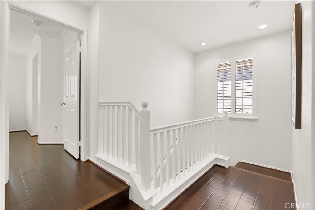 15 Poppyfield, Rancho Santa Margarita, CA 92688 Upstairs, a bright and airy landing with rich wood flooring creates an inviting transition to the home's private bedroom spaces, enhanced by natural light and classic architectural details.