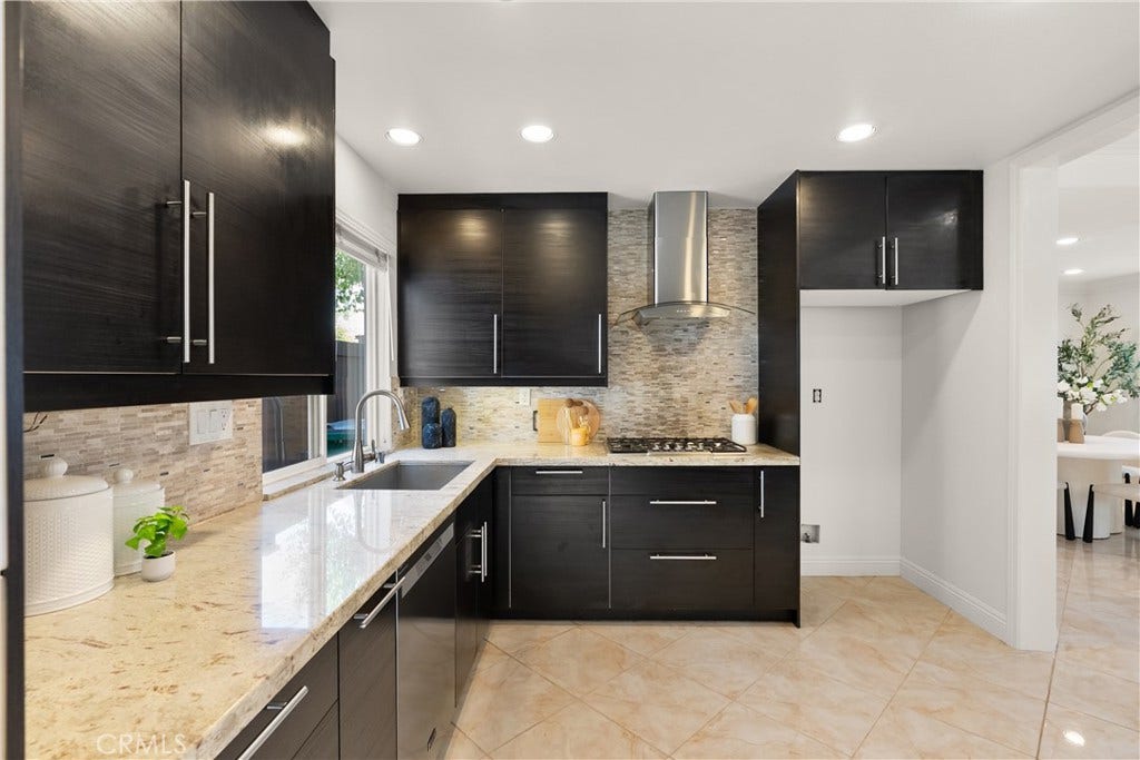 15 Poppyfield, Rancho Santa Margarita, CA 92688 The thoughtfully designed kitchen blends modern finishes with everyday functionality, highlighted by rich cabinetry, granite countertops, a designer tile backsplash, under-cabinet lighting, and a spacious layout with ample workspace.