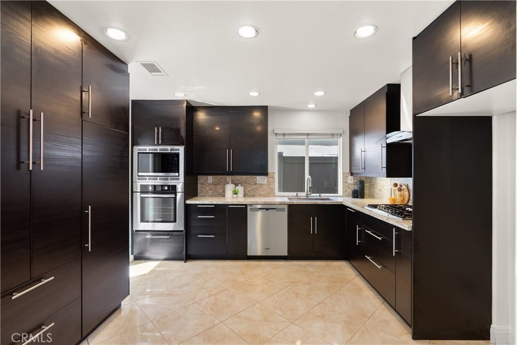 15 Poppyfield, Rancho Santa Margarita, CA 92688 Beautifully remodeled kitchen featuring rich espresso cabinetry, granite countertops, stainless steel appliances, a gas cooktop, built-in microwave and oven, extensive cabinetry, and a custom pantry wall designed to maximize storage.