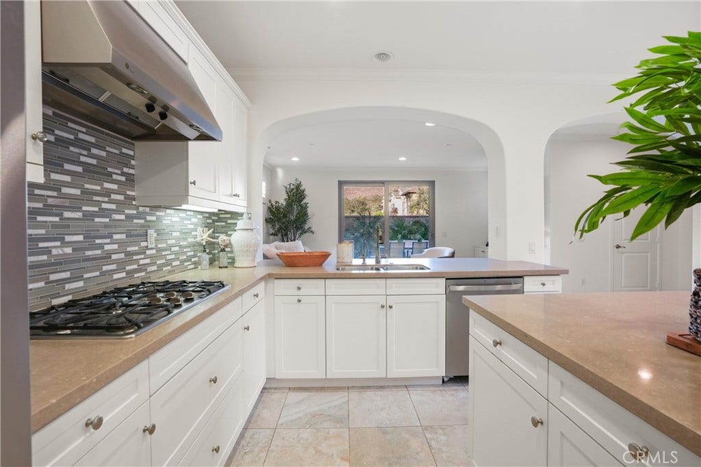 28242 Camino Del Rio, San Juan Capistrano, CA 92675 Kitchen view highlighting the gas cooktop, mosaic tile backsplash, extensive cabinetry, ample counter space, and an open connection to the family room.