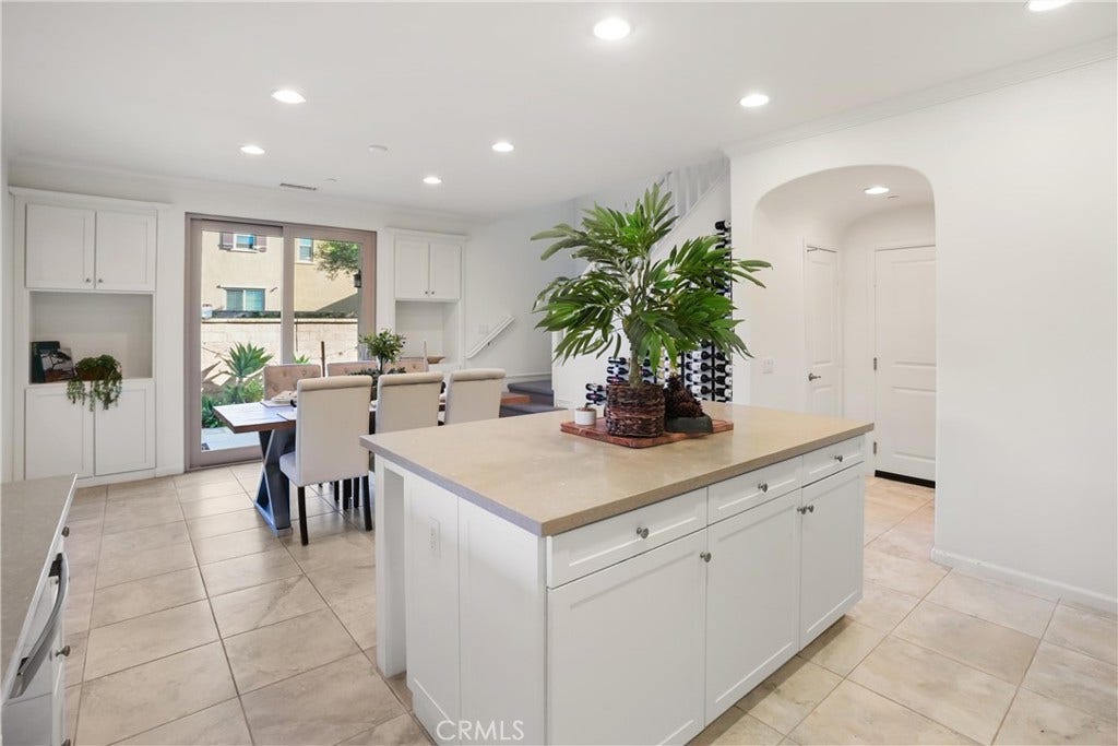 28242 Camino Del Rio, San Juan Capistrano, CA 92675 Spacious kitchen showcasing a large center island with abundant cabinetry and counter space, with the adjacent dining area and built-in storage visible beyond.
