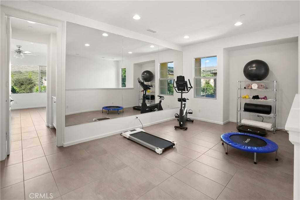 28242 Camino Del Rio, San Juan Capistrano, CA 92675 Spacious upstairs loft currently utilized as a home fitness area, featuring a mirrored wall and abundant natural light.