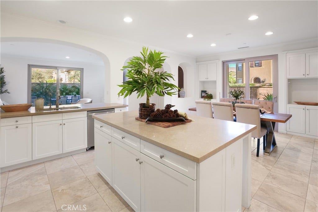 28242 Camino Del Rio, San Juan Capistrano, CA 92675 Open kitchen and dining area featuring white cabinetry, a large center island with generous storage, ample counter space, and an open flow between the kitchen and dining areas.