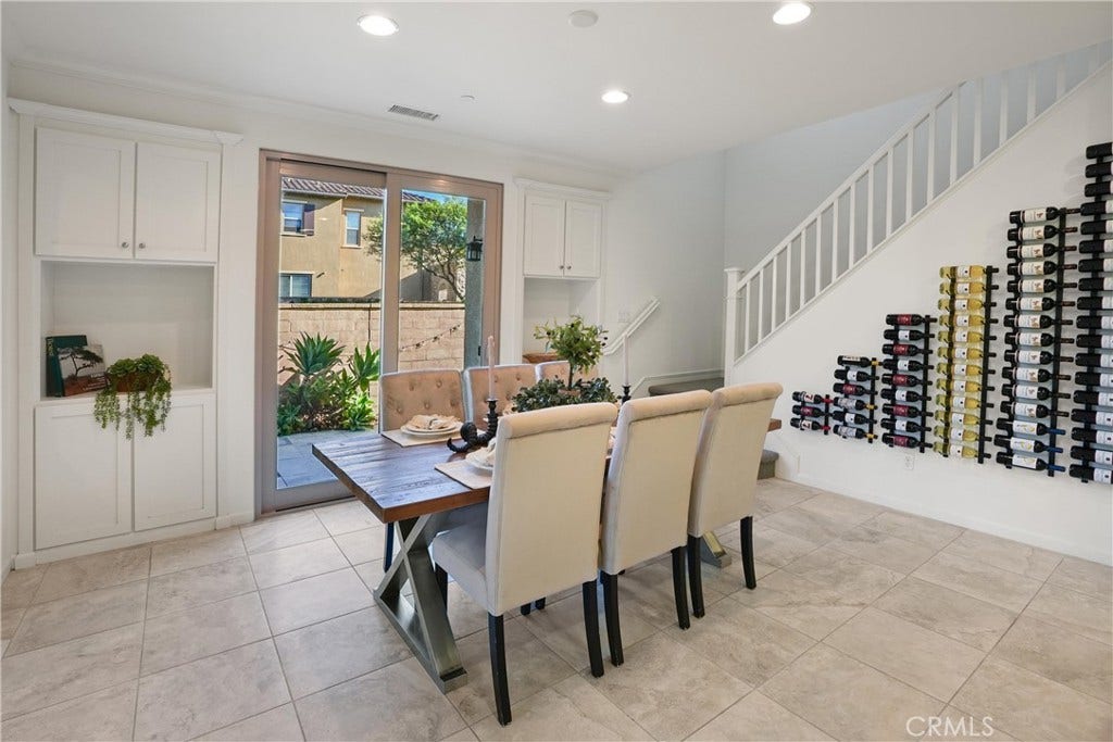 28242 Camino Del Rio, San Juan Capistrano, CA 92675 Dining area featuring built-in cabinetry, direct outdoor access, and a distinctive wall-mounted wine storage display beneath the staircase.