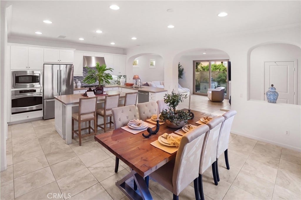 28242 Camino Del Rio, San Juan Capistrano, CA 92675 Open-concept kitchen and dining area featuring white cabinetry, stainless steel appliances, generous counter seating, recessed lighting, and a seamless flow into the adjoining living space.