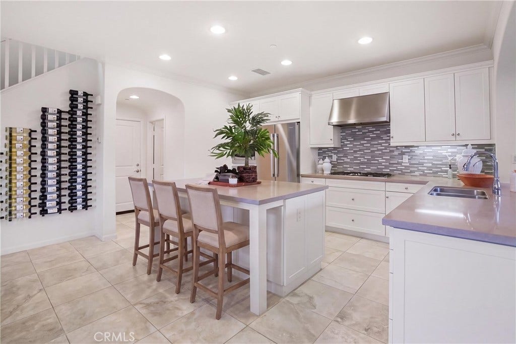 28242 Camino Del Rio, San Juan Capistrano, CA 92675 Spacious kitchen showcasing a large center island, white cabinetry, stainless steel appliances, and ample workspace.