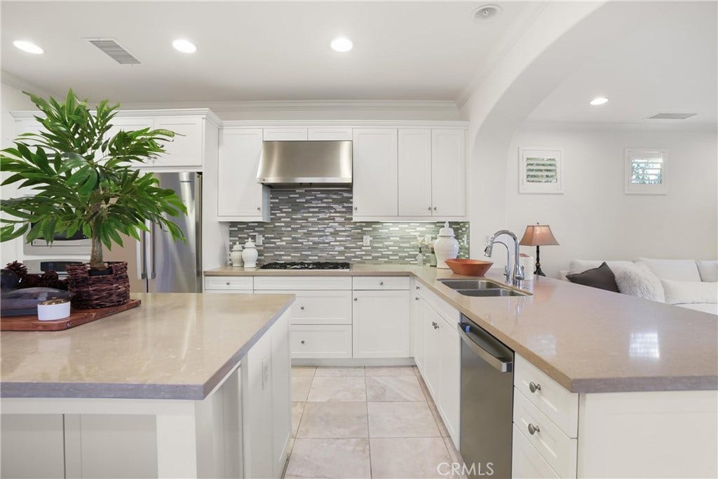 28242 Camino Del Rio, San Juan Capistrano, CA 92675 Bright kitchen featuring white cabinetry, stainless steel appliances, a gas cooktop with stainless steel hood, mosaic tile backsplash, dual-basin sink, and generous counter space.