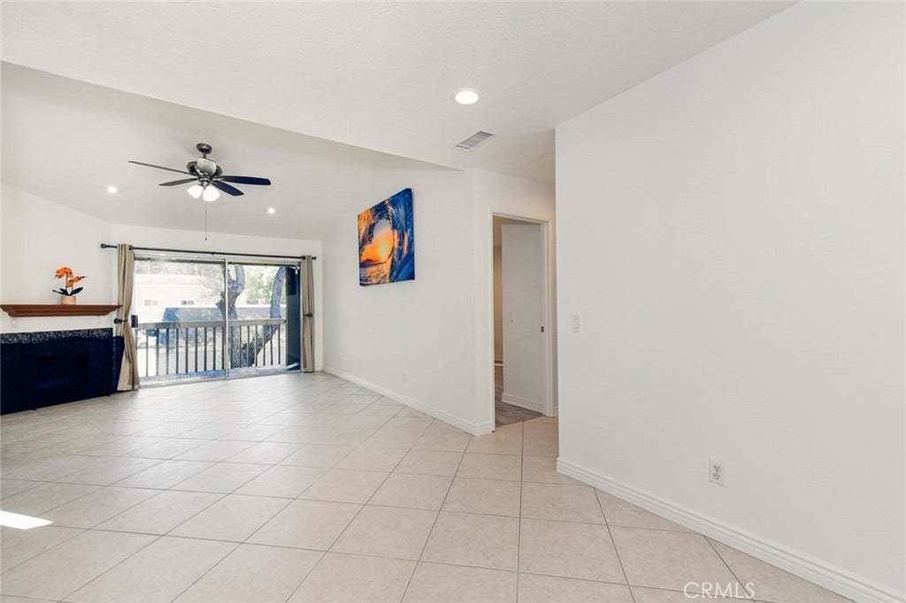 23472 Cambridge Road, #297, Yorba Linda, CA 92887 The living room has high ceiling with tile flooring, ceiling fan and the recess ceiling lights. The door on the right side is the door to the secondary bedroom.