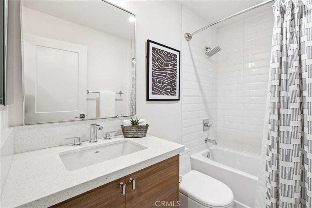 Bathroom with a tub-shower and wood vanity.