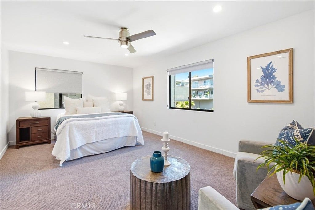 Bedroom with a ceiling fan and a sitting area.