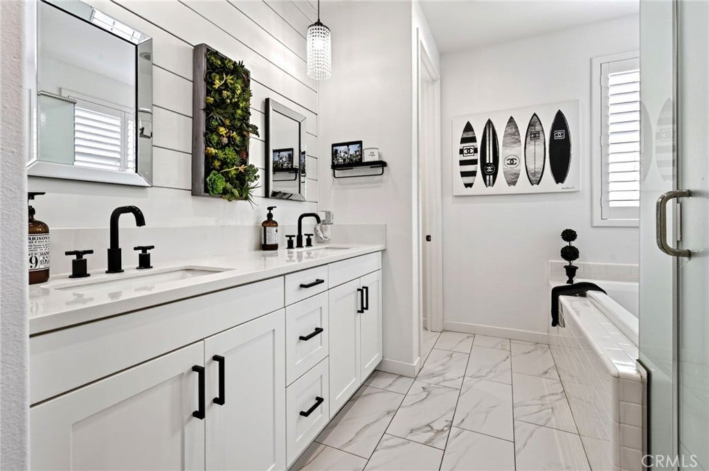 14 Marisol, Rancho Mission Viejo, CA 92694 The Primary Bathroom has a double large sink vanity with elegant touches including the beveled mirrors, pendant lighting and white shiplap accent walls. There's a walk in shower, separate soaking tub, and privacy door for the toilet with a bidet attachment.