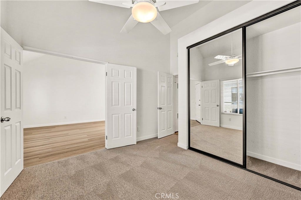 22 Aruba, Laguna Niguel, CA 92677 Double door entry into the guest bedroom, featuring a ceiling fan, mirrored closet doors, and newly installed carpeting.