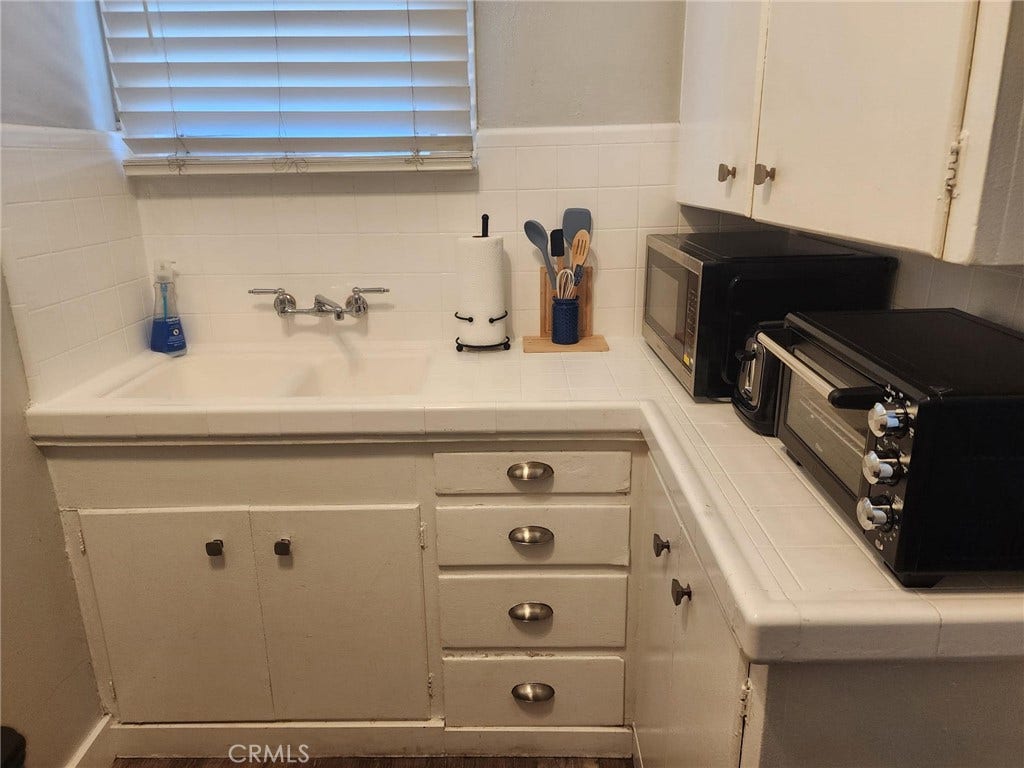 Kitchen with original tile and cupboards to maintain the feel of the 1920's building.