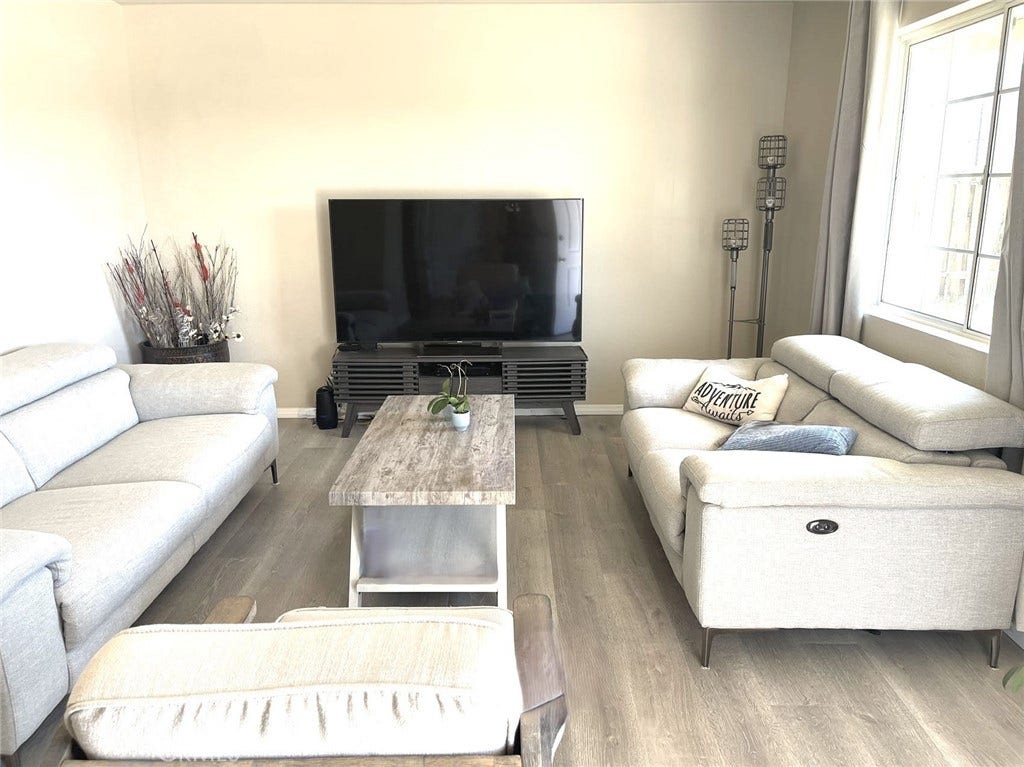 Living room with dual pane windows and laminate flooring.