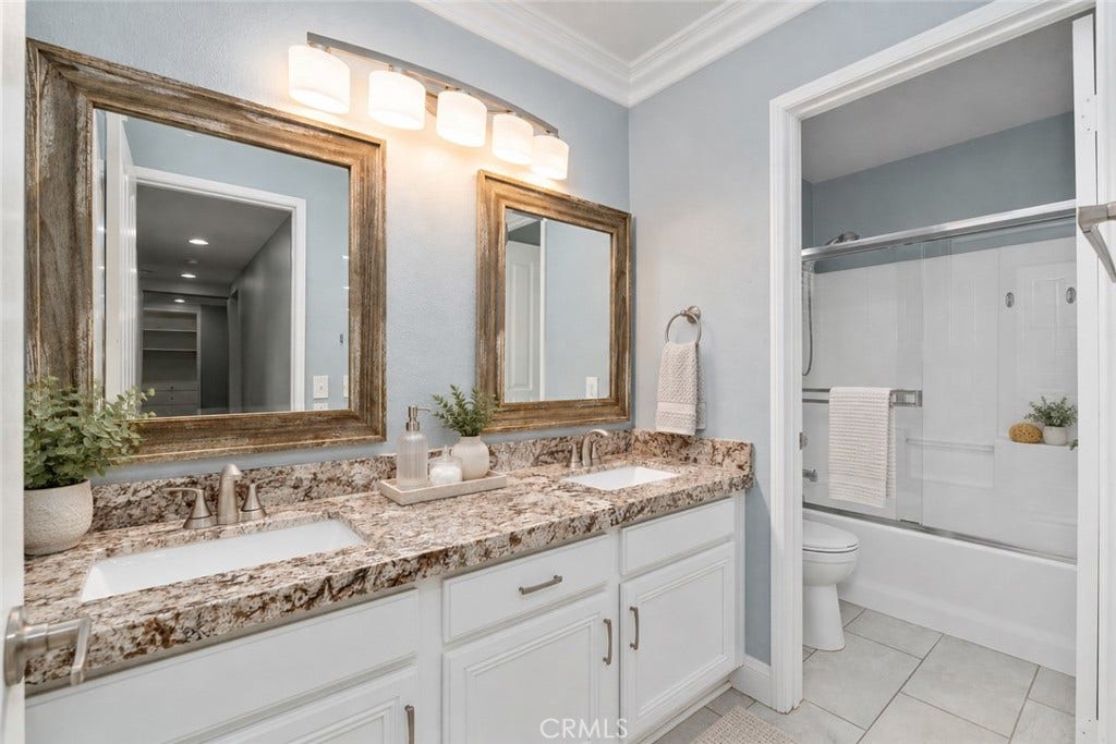32440 Magenta Court, Temecula, CA 92592 Spacious Secondary Bathroom Featuring Dual Sinks, Attractive Granite Countertops, Framed Mirrors, White Cabinetry, And A Tub And Shower Combination. Digitally Staged